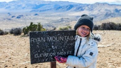 girl next to Ryan Mountain Hike sign at the summit
