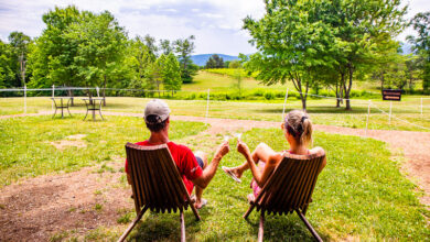 man and woman on chhers cheersing their wine looking at view