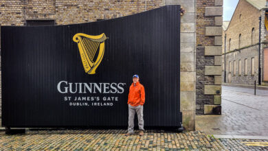 Man standing in front of a large black gate with the words Guinness
