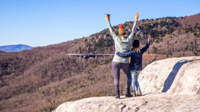 people standing on a boulder in the mountains